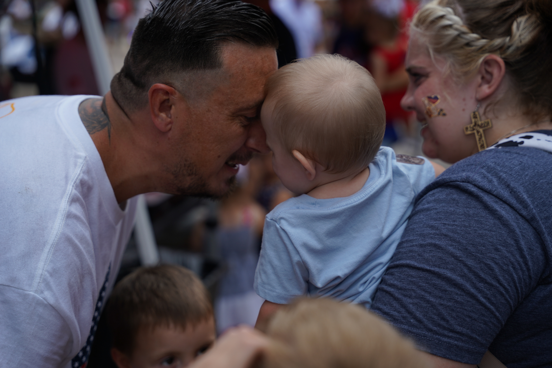 A father gently touching foreheads with his baby while the mother smiles nearby